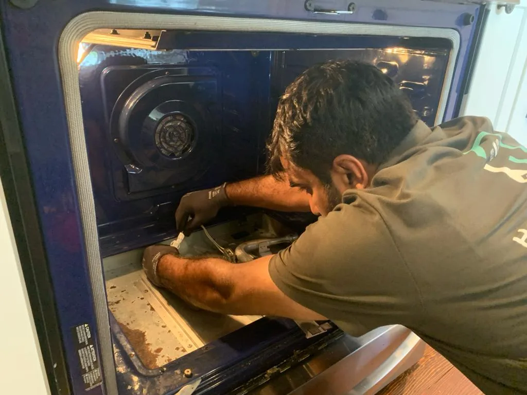 Professional appliance repair technician fixing oven